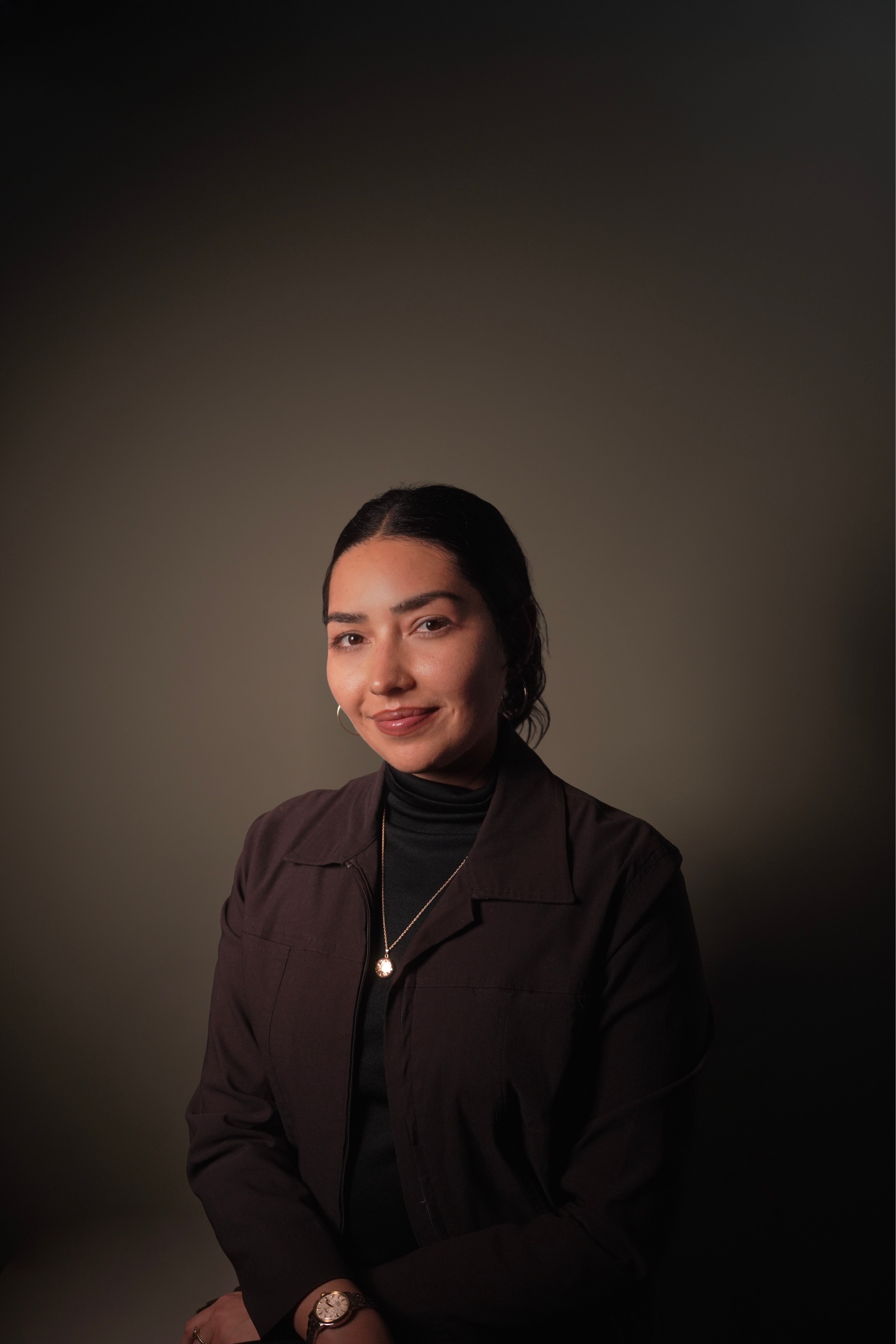 Portrait of a woman with brown hair on a flat gray background.